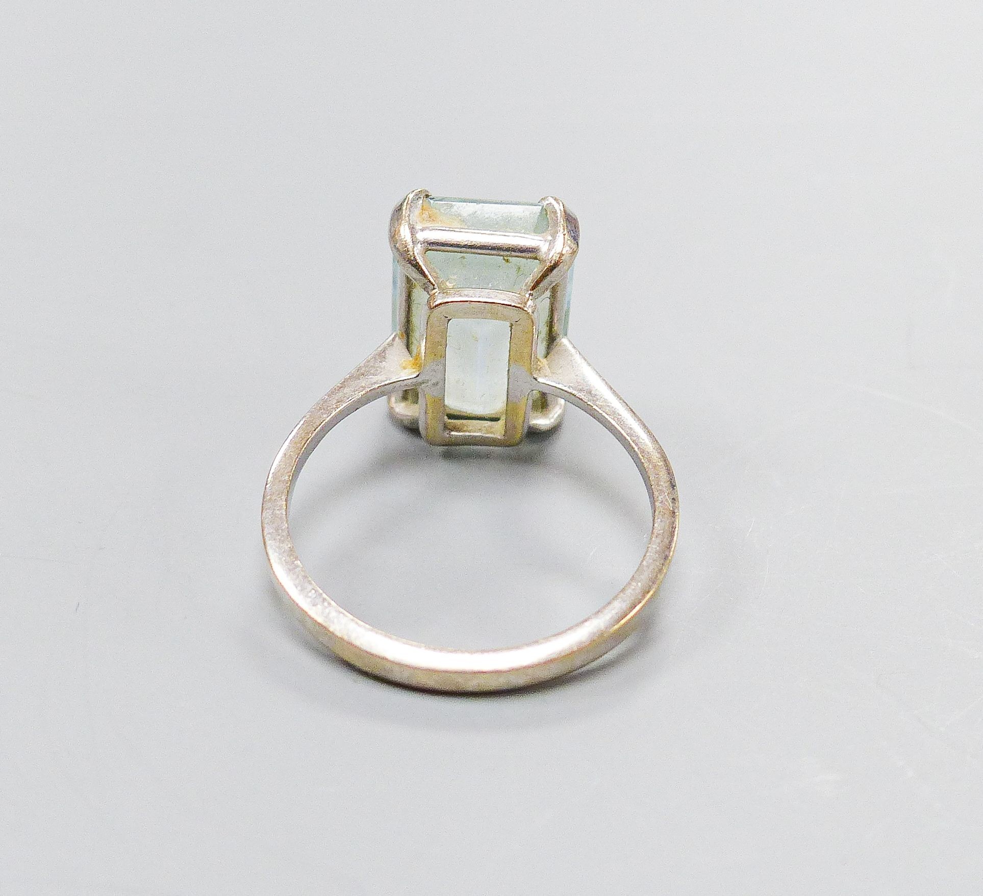 A 750 white metal and emerald cut aquamarine set ring, size O, gross weight 4.6 grams.